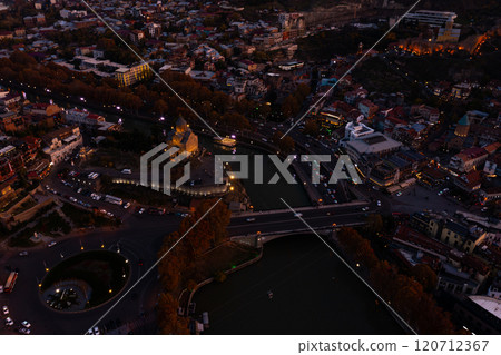 Capturing the enchanting autumn nights of Tbilisi with vibrant city lights and gentle river reflections 120712367