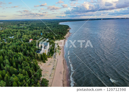 Aerial view of a serene coastline surrounded by lush forests near a calm body of water at twilight Aerial view of a serene coastline surrounded by lush forests near a calm body of water at twilight 120712398