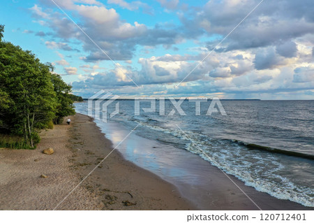 Serene lakeside beach walk at sunset with shifting clouds and rippling water 120712401