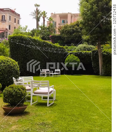 white chairs on a green lawn in a park 120712438