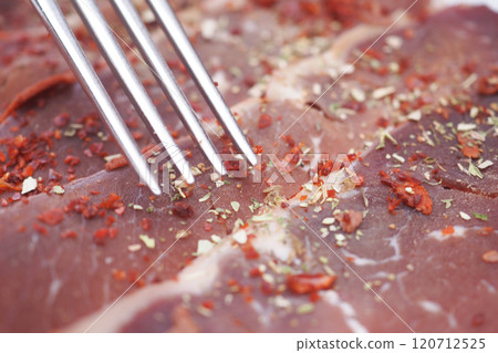 Close-Up of Seasoned Raw Meat with Metal Fork Close-Up of Seasoned Raw Meat with Metal Fork 120712525