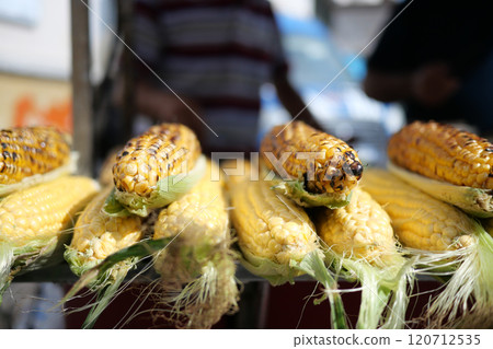 Grilling a delicious ear of corn on the cob during a sunny and warm summer day outdoors 120712535