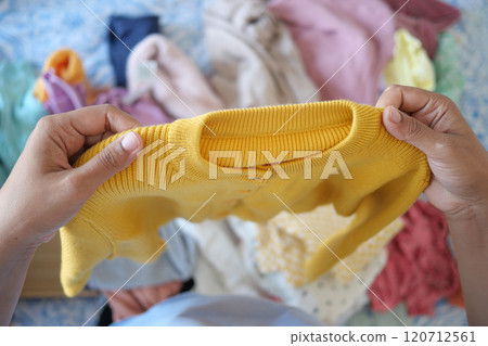 Organizing and Sorting Colorful Clothing A CloseUp Observational Look at a Yellow Sweater Organizing and Sorting Colorful Clothing A CloseUp Observational Look at a Yellow Sweater 120712561