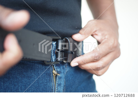 Making adjustments to a belt on a stylish pair of jeans for a perfect, comfortable fit Making adjustments to a belt on a stylish pair of jeans for a perfect, comfortable fit 120712688
