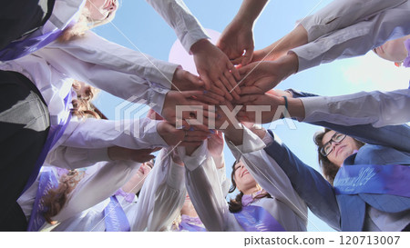 Graduating students gather in a circle, holding hands, commemorating their final day of school and representing unity, friendship, and achievement Graduating students gather in a circle, holding hands, commemorating their final day of school and representing unity, friendship, and achievement 120713007