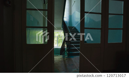 Light streaming through open doors illuminates a shadowy hallway and staircase in an empty school on the last day Light streaming through open doors illuminates a shadowy hallway and staircase in an empty school on the last day 120713017