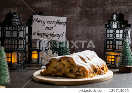 Greeting card with message MERRY EVERYTHING AND A HAPPY ALWAYS. Christmas Stollen in Christmas lights and decoration. Traditional sweet fruit loaf with icing sugar festive pastry dessert. Holiday Greeting card with message MERRY EVERYTHING AND A HAPPY ALWAYS. Christmas Stollen in Christmas lights and decoration. Traditional sweet fruit loaf with icing sugar festive pastry dessert. Holiday 120713655