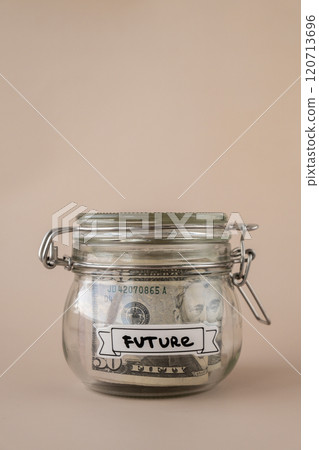 Glass jar full of American currency dollars cash banknote with text FUTURE. Preparation saving money. Moderate consumption and economy Glass jar full of American currency dollars cash banknote with text FUTURE. Preparation saving money. Moderate consumption and economy 120713696