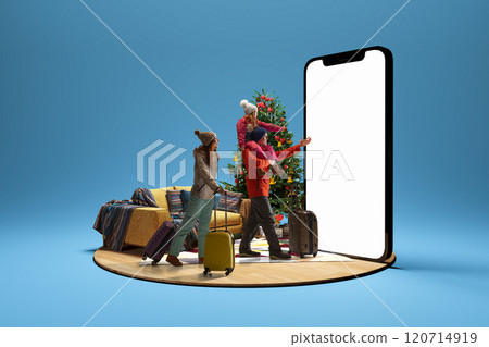 Family with suitcases and child on father shoulders walking towards large 3D model of smartphone with blank screen with Christmas tree in background. 120714919