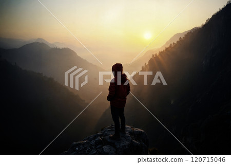 Hiker admiring a stunning mountain landscape at sunrise 120715046