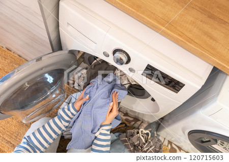 Female housewife hands putting dirty clothes textile to washing machine at laundry top view closeup Female housewife hands putting dirty clothes textile to washing machine at laundry top view closeup 120715603