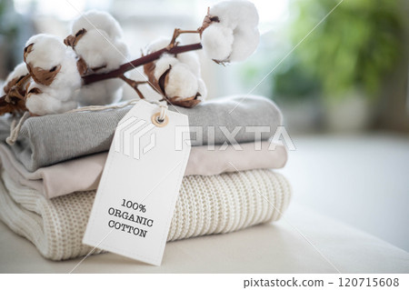 A neat stack of knitted clothing labeled 100 percent organic cotton. White background. 120715608