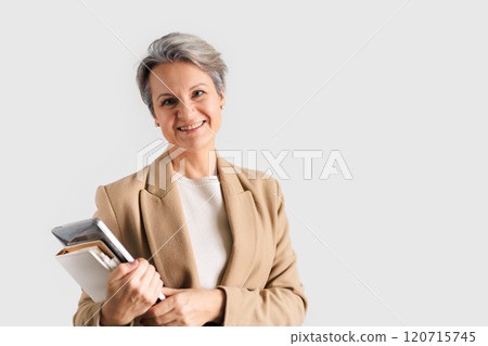 A beautiful middle-aged European woman with gray hair smiles and holds a laptop  120715745