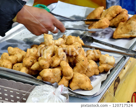 A vendor is placing freshly fried Chinese crullers into a bag to sell to a customer A vendor is placing freshly fried Chinese crullers into a bag to sell to a customer 120717524