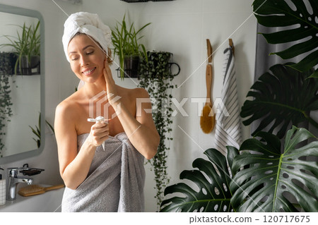 A well-groomed and beautiful woman combs her hair in front of a mirror in her bathroom. A well-groomed and beautiful woman combs her hair in front of a mirror in her bathroom. 120717675