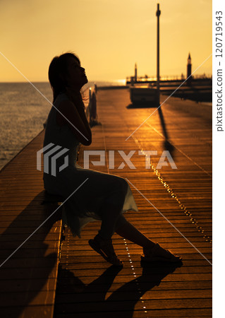 在海洋甲板上看日落的女人 120719543