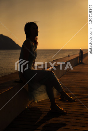 Woman watching the sunset on a sea deck 120719545