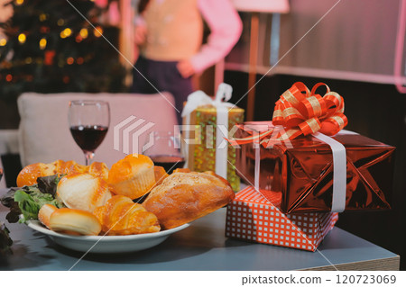 Group of young Asian man and women as friends having fun at a New Year's celebration, holding gift boxes standing by Christmas tree decoration, midnight countdown Party at home with holiday season. 120723069