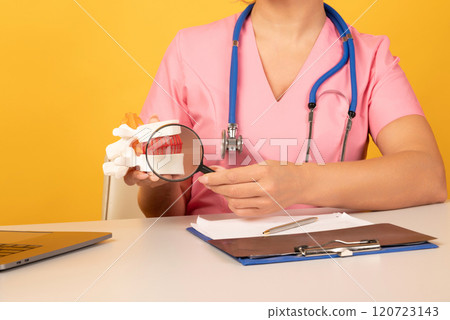 Doctor showing a Anatomical lumbar disc herniation model using magnifying glass. Early diagnosis and treatment. Doctor showing a Anatomical lumbar disc herniation model using magnifying glass. Early diagnosis and treatment. 120723143