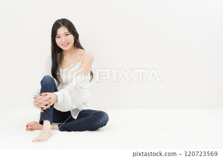 一位年輕女子穿著緊身牛仔褲、牛仔褲和牛仔褲，盤腿而坐 120723569