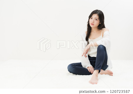 一位年輕女子穿著緊身牛仔褲、牛仔褲和牛仔褲，盤腿而坐 120723587