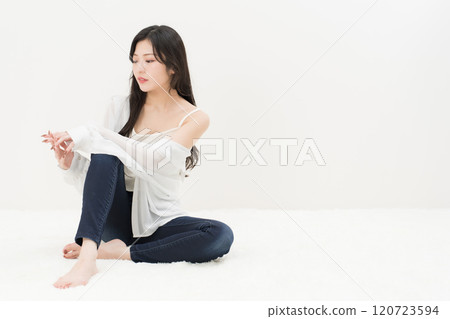 一位年輕女子穿著緊身牛仔褲、牛仔褲和牛仔褲，盤腿而坐 120723594