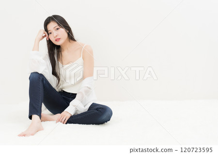 一位年輕女子穿著緊身牛仔褲、牛仔褲和牛仔褲，盤腿而坐 120723595