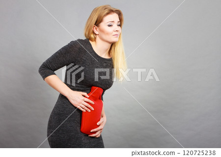 Girl having stomach ache, holding hot water bottle Girl having stomach ache, holding hot water bottle 120725238