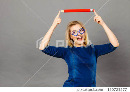 Smiling woman holds big pencil in hand 120725277