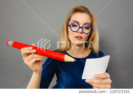 Serious woman holds big pencil note paper in hand 120725281