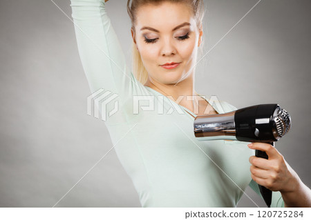 Woman drying armpit with hair dryer Woman drying armpit with hair dryer 120725284