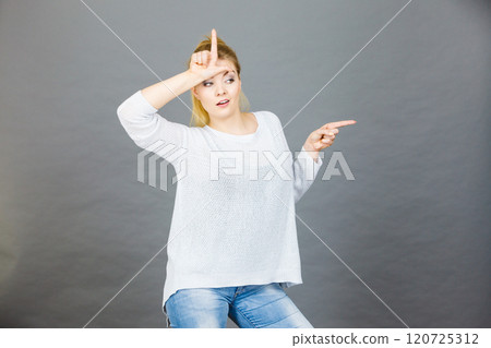 Woman showing loser gesture with L on forehead 120725312