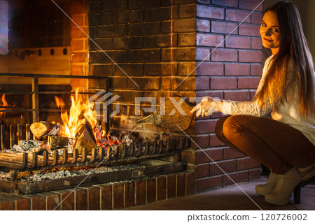 Woman at home fireplace making fire with bellows. Woman at home fireplace making fire with bellows. 120726002