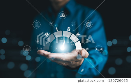 Risk Management and Assessment Concept. A person holding digital risk gauge in their hand, with icons represents various aspects of risk management and assessment, indicating different levels of risk. 120726055