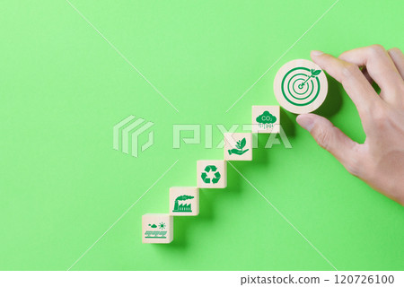 Green Energy and Sustainable Concept. Hand holding a wooden block a target with a leaf, with green energy and sustainability icons on a green background. Carbon footprint, global warming, net zero, Green Energy and Sustainable Concept. Hand holding a wooden block a target with a leaf, with green energy and sustainability icons on a green background. Carbon footprint, global warming, net zero, 120726100