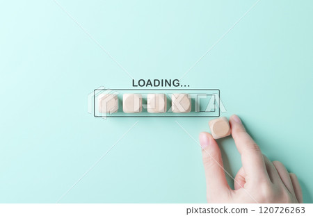 Loading bar concept. Progress bar, A hand placing a wooden block into a loading bar made of blocks, set against a mint green background, representing progress, patience, update, or waiting. Loading bar concept. Progress bar, A hand placing a wooden block into a loading bar made of blocks, set against a mint green background, representing progress, patience, update, or waiting. 120726263