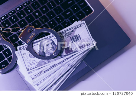Cyber crime. Handcuffs on a hundred dollar bills on laptop 120727040