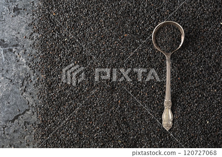 Black sesame seeds and spoon on a black stone table. Black sesame seeds and spoon on a black stone table. 120727068