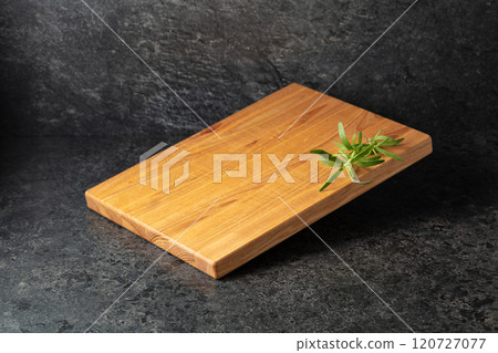 Empty cutting board with rosemary on a black stone background. 120727077