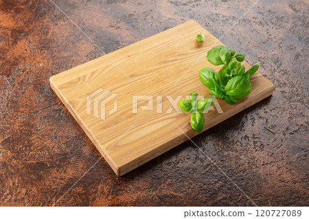Cutting board and basil on a brown kitchen table. Cutting board and basil on a brown kitchen table. 120727089