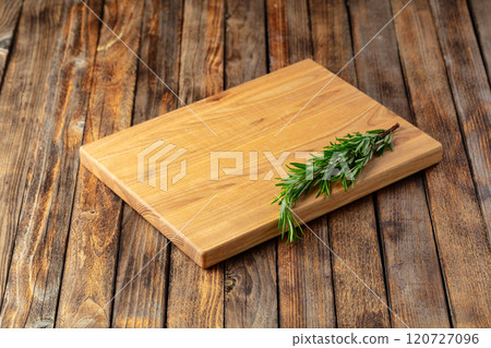Cutting board and rosemary on an old wooden table. Cutting board and rosemary on an old wooden table. 120727096