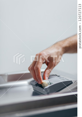 Man putting detergent tablet into open dishwasher indoors, closeup Man putting detergent tablet into open dishwasher indoors, closeup 120727113