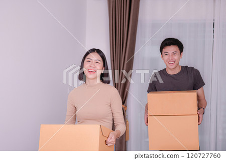 Happy couple moving boxes indoors together. 120727760