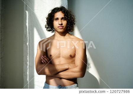 Portrait of topless serious handsome man with crossed arms illumed with daylight standing still for photo Portrait of topless serious handsome man with crossed arms illumed with daylight standing still for photo 120727986