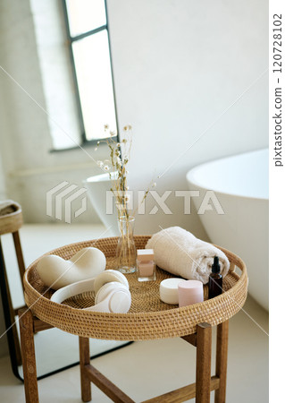 Vertical high angle shot of white headphones, rolled towel and perfumed oils and moisturizing cream on top of table in bathroom Vertical high angle shot of white headphones, rolled towel and perfumed oils and moisturizing cream on top of table in bathroom 120728102