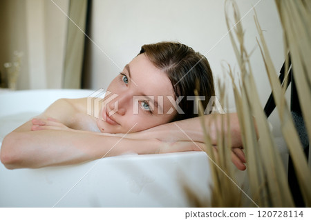 Medium close up portrait of Caucasian woman with big ice blue eyes and no makeup on face lying in bath and posing for photo Medium close up portrait of Caucasian woman with big ice blue eyes and no makeup on face lying in bath and posing for photo 120728114