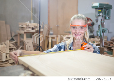young carpenter women using measuring tape looking wood size making furniture in joinery. craftsman profession in wood factory. professional furniture woodwork. young carpenter women using measuring tape looking wood size making furniture in joinery. craftsman profession in wood factory. professional furniture woodwork. 120728293