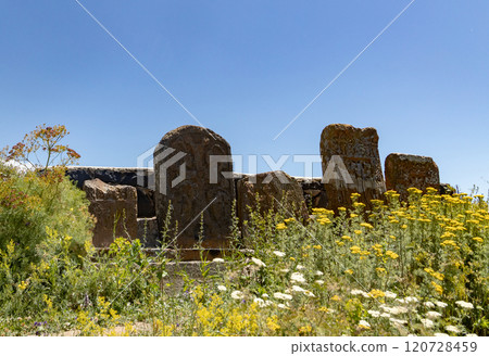 Ancient Sevanavank Monastery in Armenia surrounded by vibrant wildflowers under a clear blue sky 120728459