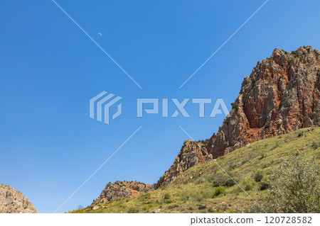 Noravank monastery stands proud against the backdrop of red mountains under a clear blue sky in Armenia 120728582