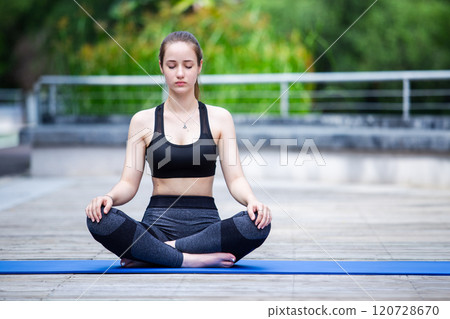 Beautiful women sportswear practicing yoga sitting pose stretching legs and folded hands. Prayer position yoga outdoor on floor. Relaxation yoga exercise concept. 120728670